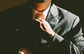 man in suit straightening tie