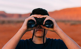 man looking into future through binoculars