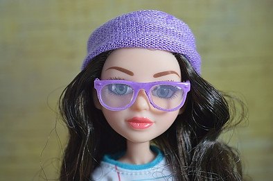 Toy doll with black hair, purple glasses and purple hat